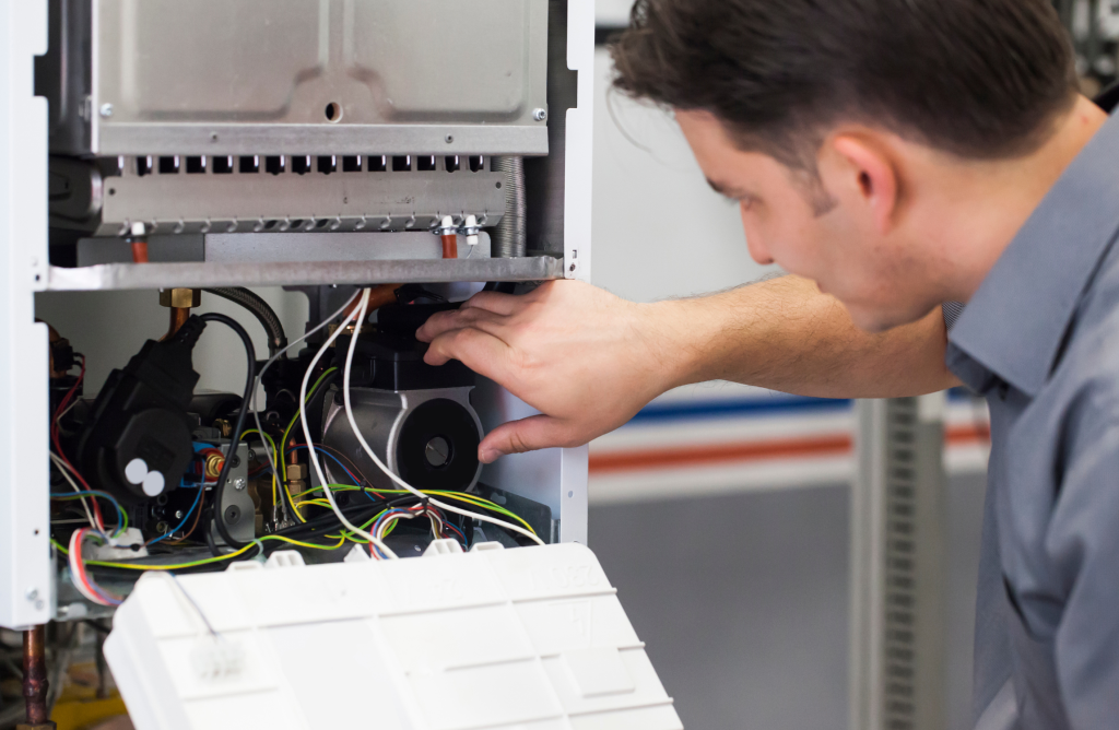 Vista ravvicinata di una caldaia ibrida aperta durante un intervento di manutenzione. Tecnico specializzato esamina i componenti interni utilizzando strumenti diagnostici, garantendo efficienza energetica.