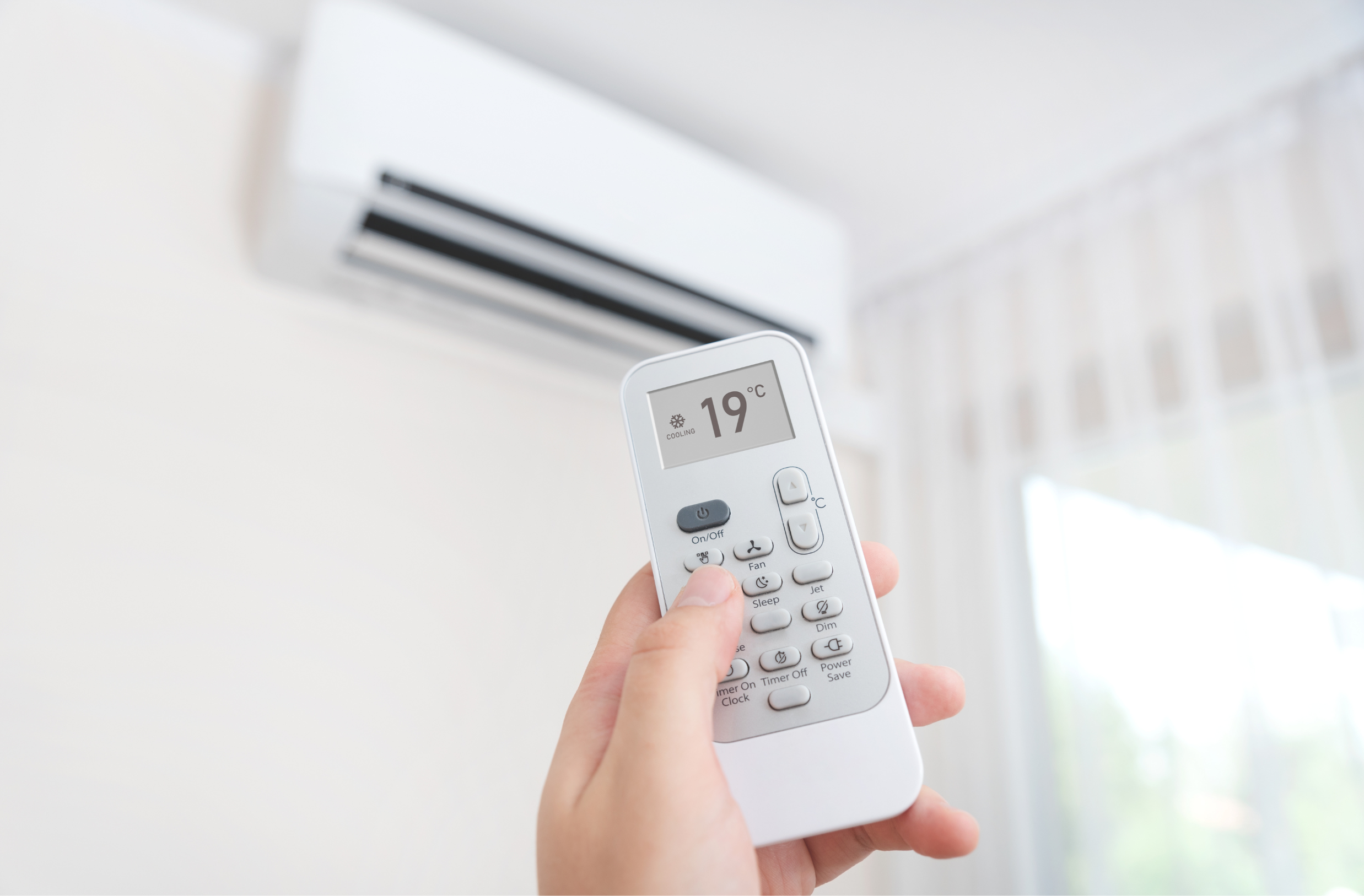 Mano che accende un condizionatore a basso consumo tramite telecomando con tecnologia inverter, unità interna in funzione