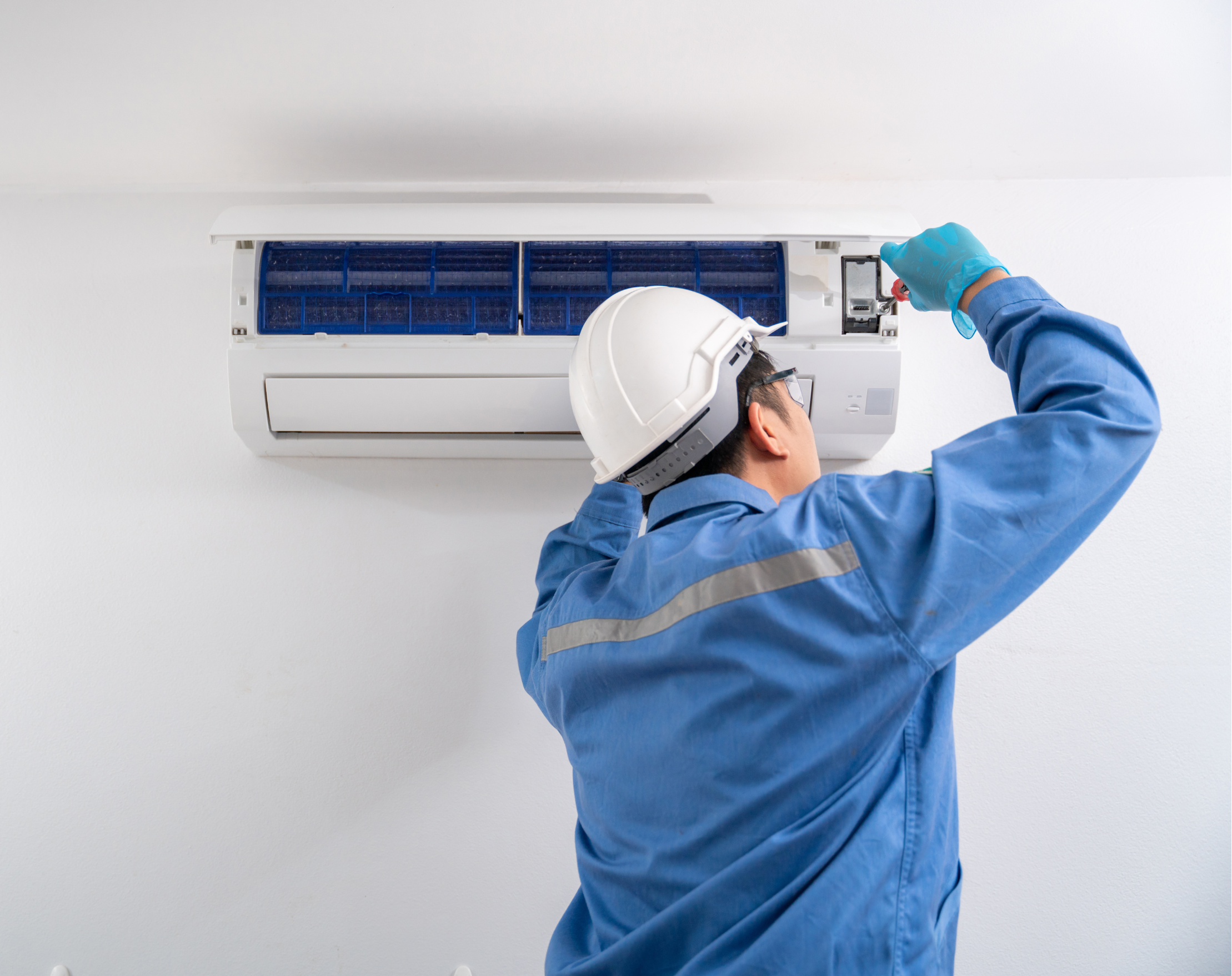 Operaio specializzato installa l'unità interna di un condizionatore split a parete, regolando i supporti e collegando i tubi del refrigerante.